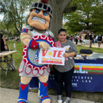 Maryam poses with University of Detroit Mercy mascot pose with a Vote Our Future sign.