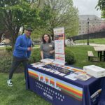 Baylee stands behind a table with the Y.A.L.L. banner and materials