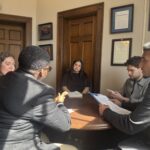 Four YALL students sit around a wooden circular table while speaking to a staffer from Rep. Torres' office.
